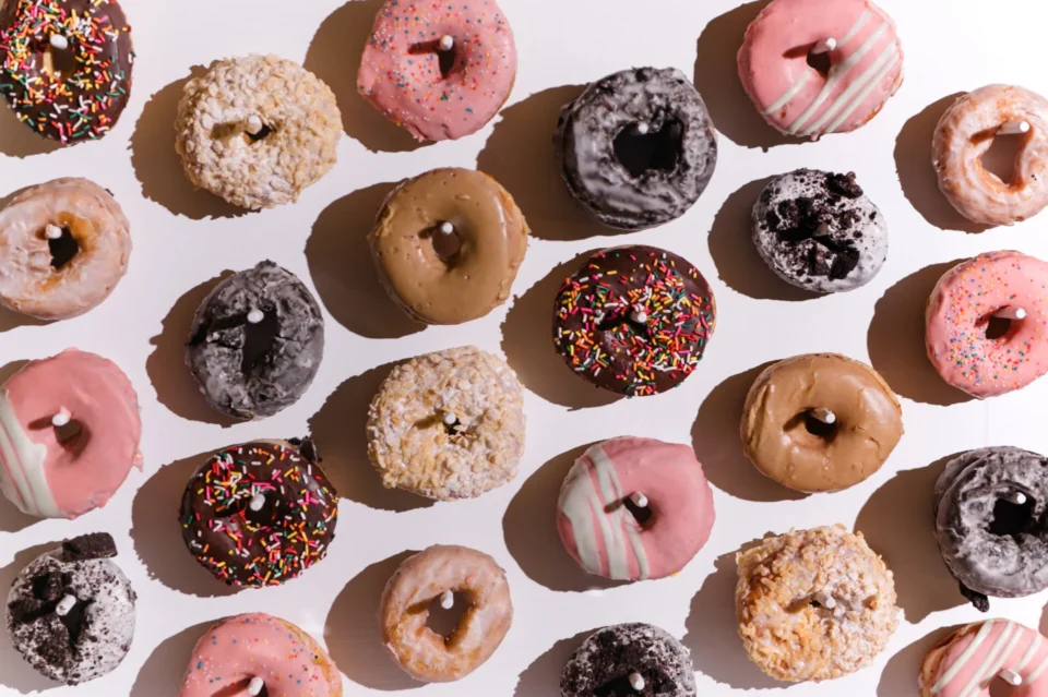 A colorful assortment of donuts featuring various toppings, including sprinkles, chocolate, and icing, arranged in an inviting pattern.
